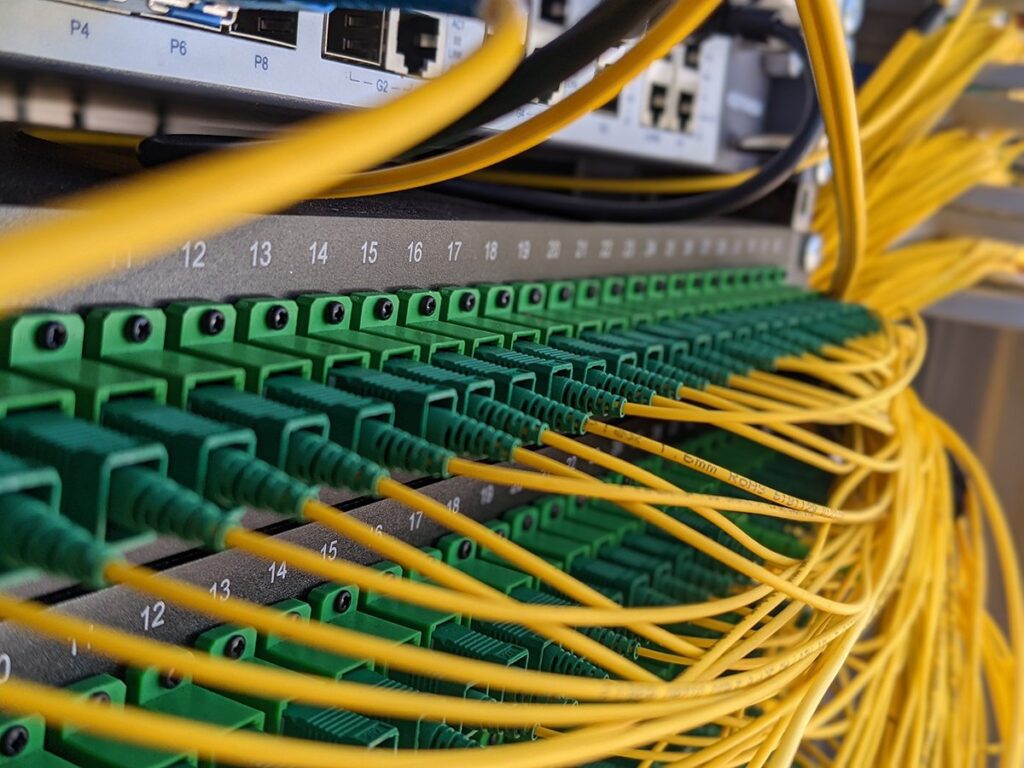 Yellow fiber cable with green connector boots nicely arranged with structure cabling in mind